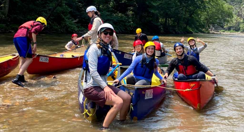 a group of students sitting in canoes prepare to navigate whitewater on an outward bound expedition 